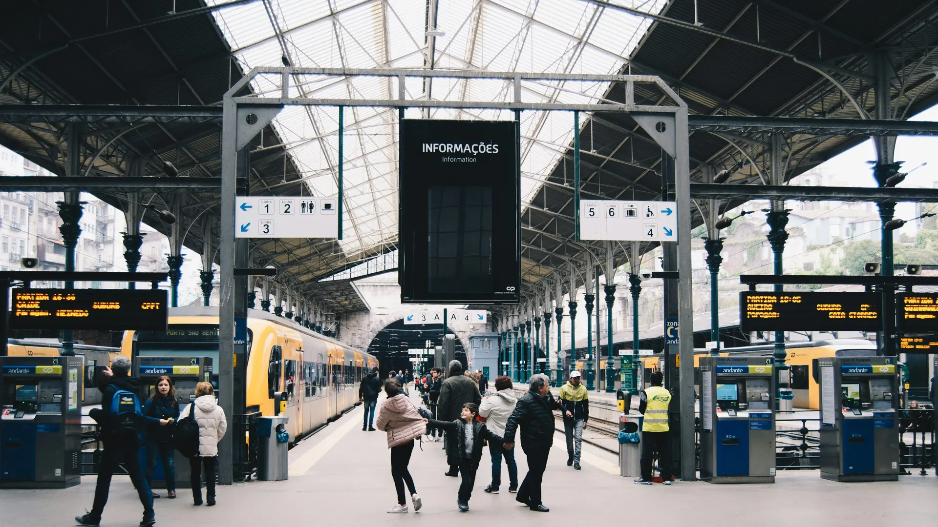 Reizigers lopen door een drukke stationshal langs de sporen
