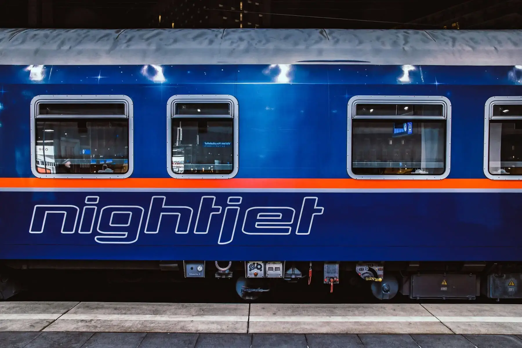 Nightjet-rijtuig met blauw-oranje livrei op het perron